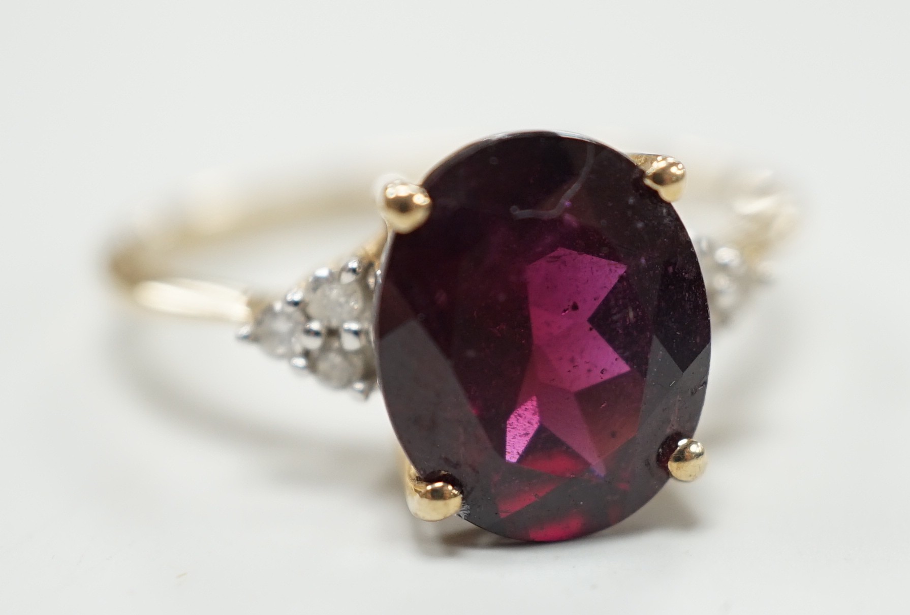 A modern 9ct gold, single stone oval cut garnet and six stone diamond chip set dress ring, size R/S, gross weight 2.8 grams.